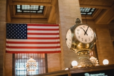 America's News resource image depicting what looks to be the interior of a train station with a clock and American flag