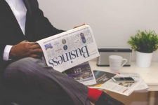 Business Source Premier resource image showing a man in a business suit holding the "Business" section of the newspaper