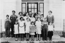 WLSDC; Winnebago County Rural Schools resource image of a black and white historical photo of a class standing in front of a schoolhouse