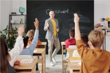 ERIC (Education Resources Information Center) resource image showing a male teacher at the head of a classroom with middle-school aged students raising their hands