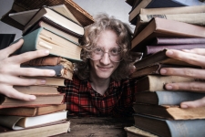 Explora for Middle & High Schools resource image showing a student smiling between two large stacks of books