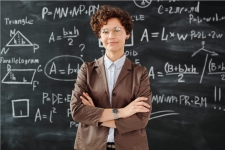 Education Research Complete resource image showing an older woman teacher standing in front of a chalkboard full of equations