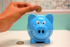 Gale Courses; Personal Finance & Investments resource image showing a person putting a coin in a blue piggybank