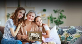 HeritageHub resource image showing a grandmother, a mother and her daughter all smiling and holding a framed sepia photo