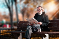 Milwaukee Journal-Sentinel Collection resource image showing an older man sitting on a bench while reading a newspaper