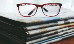 NewspaperARCHIVE resource image showing a stack of newspapers with reading glasses folder on top