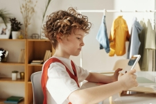 Overdrive/Libby for Kids resource image showing a boy at a desk in his room holding a tablet