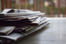 Oshkosh Northwestern via Proquest resource image showing a stack of newspapers on a table