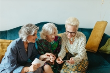 Oshkosh Stories & Snapshots resource image showing a group of three senior women looking at photos on a couch