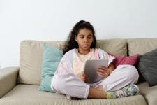 Overdrive/Libby for Teens resource image showing a teenage girl sitting cross-legged on a couch with a tablet in her hands