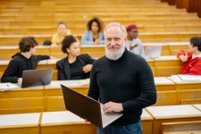 Professional Development Collection resource image depicting a male professor holding a laptop in front of his college-aged students