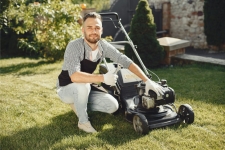 Small Engine Repair Source resource image showing a man leaning down next to a push mower