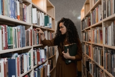 Senior High Core Collection resource image showing a teen girl looking through books on a library bookshelf