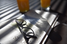 US Newsstream resource image showing a folded newspaper with reading glasses sitting on top