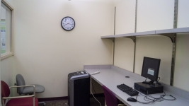 Multipurpose room with computer, chair, and shredder.