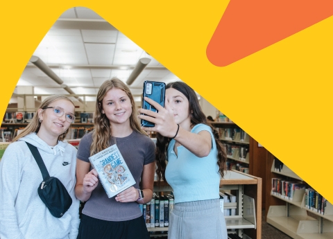 3 teens posing for a photo with their book. 